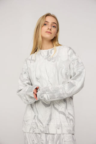 Woman wearing a white patterned outfit against a plain background