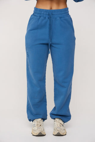 Blue sweatpants worn by a person on a white background