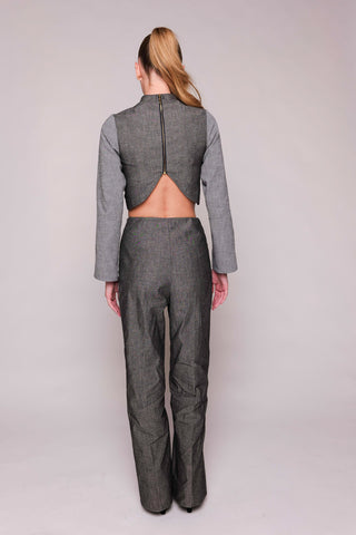 Person wearing a gray outfit with an open back on a plain background
