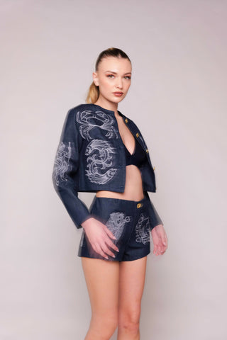 Woman wearing a navy blue outfit with white embroidery on a plain background