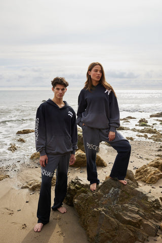 A group of models in coordinated zodiac themed loungewear, featuring a gradient ombre dip-dye, adjustable waistbands, and flared bottoms, all made from premium materials.