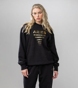 Black crewneck with "Aries" and list of personality traits in reflective gold foil.