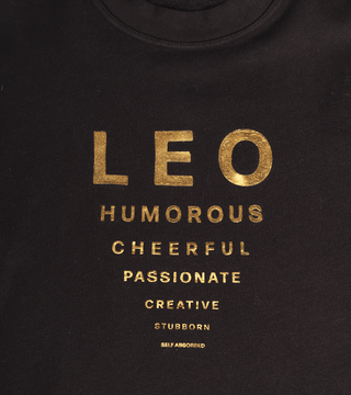 black crewneck with gold reflective foil reading "Leo, Humorous, Cheerful, Passionate, Creative, Stubborn, Self Absorbed."